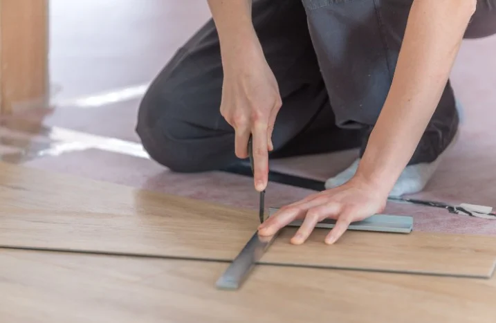 Person schneidet Vinylboden mit Cuttermesser